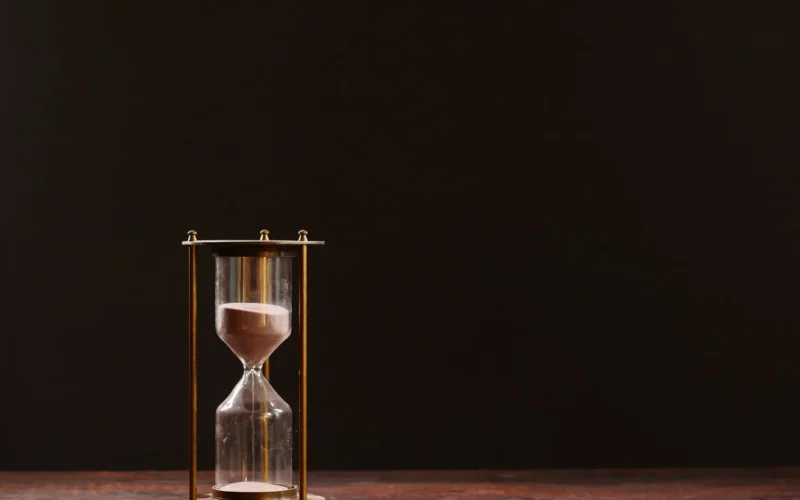 Brass hourglass on a dark table, a stand-in for the install delay that stops a malicious Claude Code extension