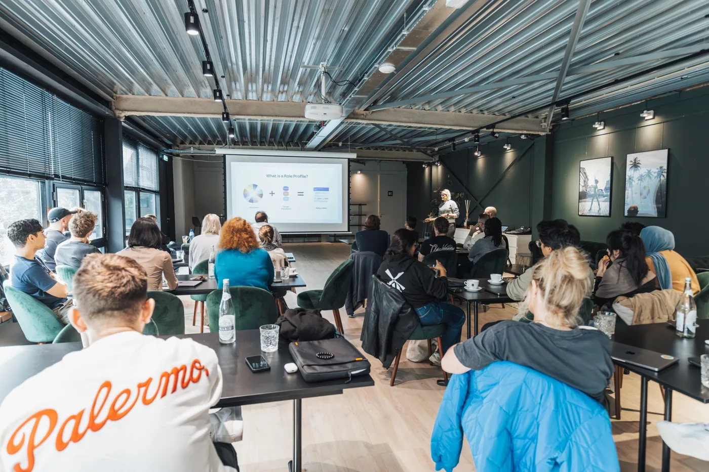 Staff in a training room watching a slide presentation on a large screen.