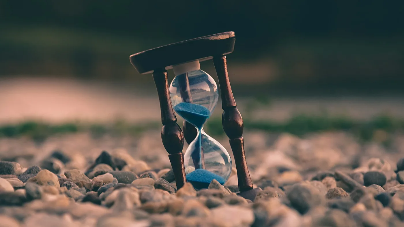A brown and blue hourglass standing on stones.
