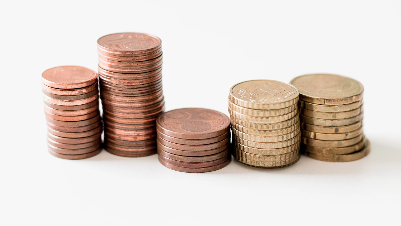 Stacks of copper and gold coins of different heights on a white surface