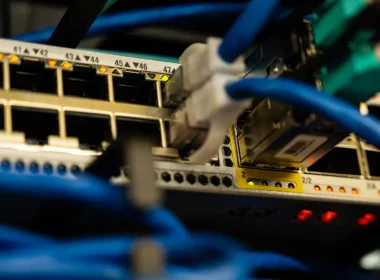 Blue Ethernet cables plugged into the ports of a network switch with small status lights