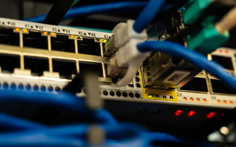 Blue Ethernet cables plugged into the ports of a network switch with small status lights