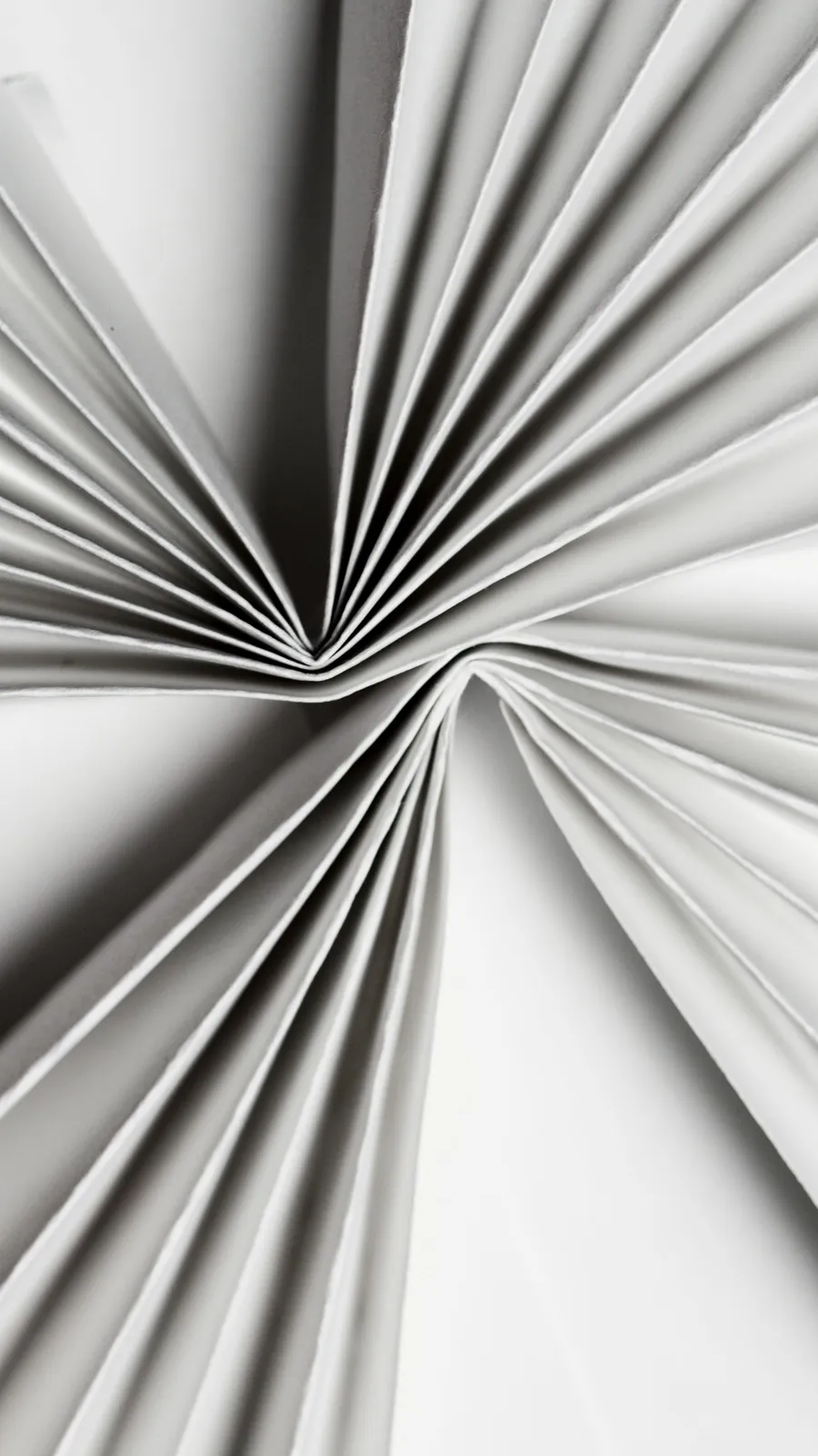 Folded white paper fanning out in shadow, an abstract image of layered payment checks
