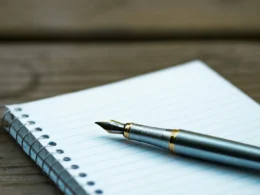 A fountain pen resting on an open spiral notebook