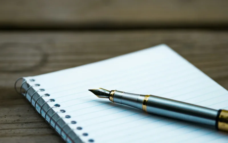 A fountain pen resting on an open spiral notebook