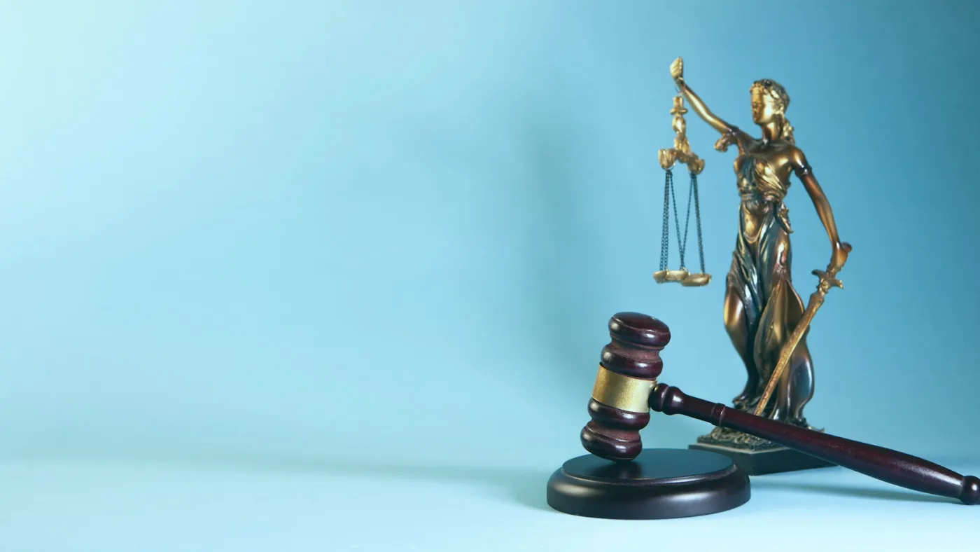 Lady Justice statuette and gavel against a blue background.