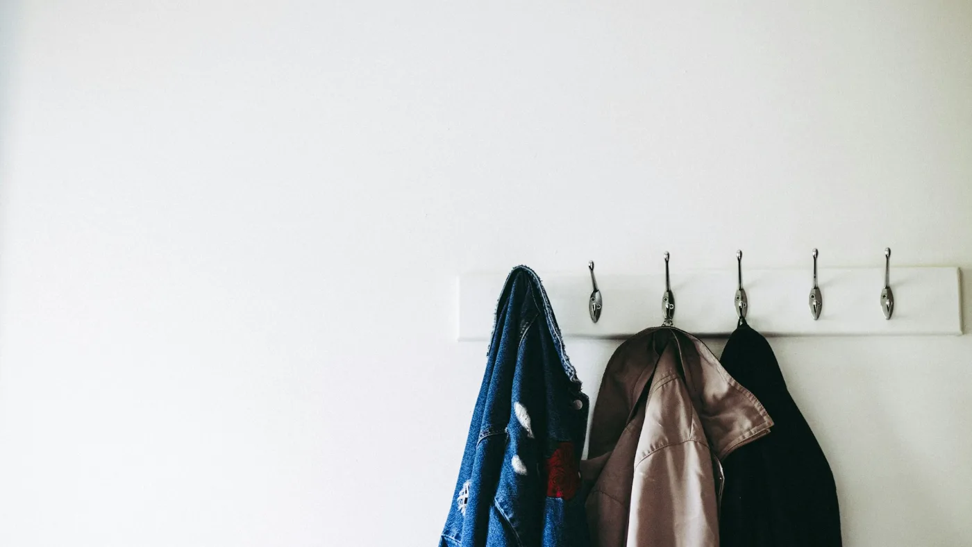 Three jackets hanging on wall hooks