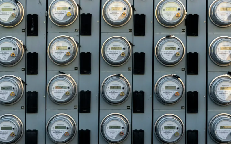 A grey electric utility meter mounted on an outside wall