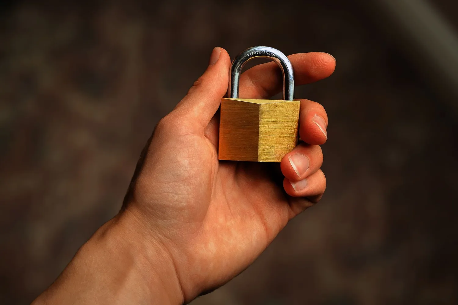 Hand holding a brass padlock, for the AI agents bank login rule against sharing passwords