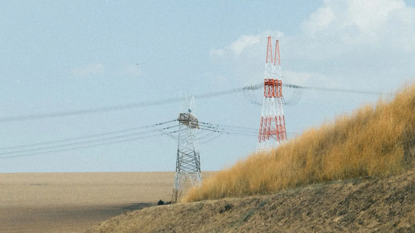 High-voltage transmission towers on a dry prairie field, the power question behind the Calgary data centre moratorium