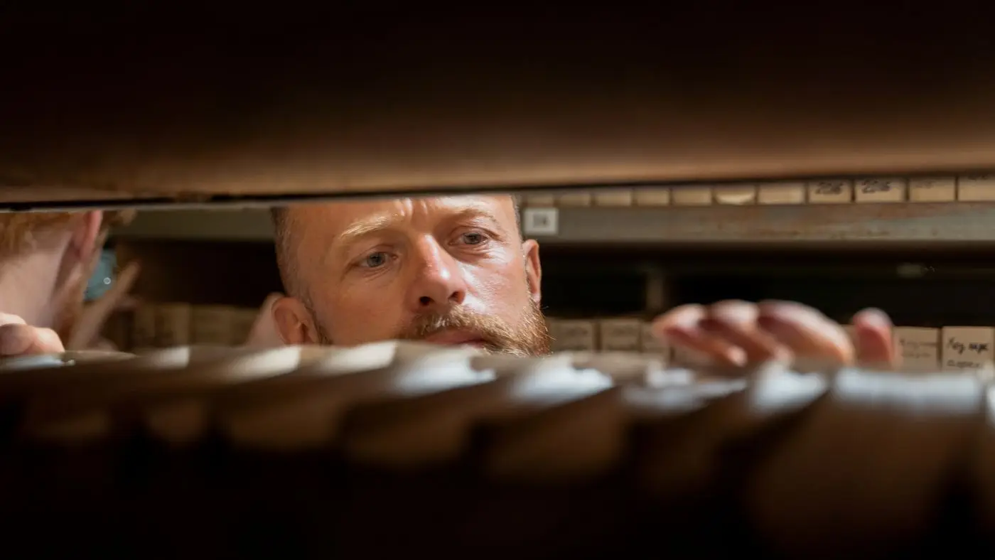 Man searching a shelf of archived files, the kind of records the Alberta deepfake law puts under review