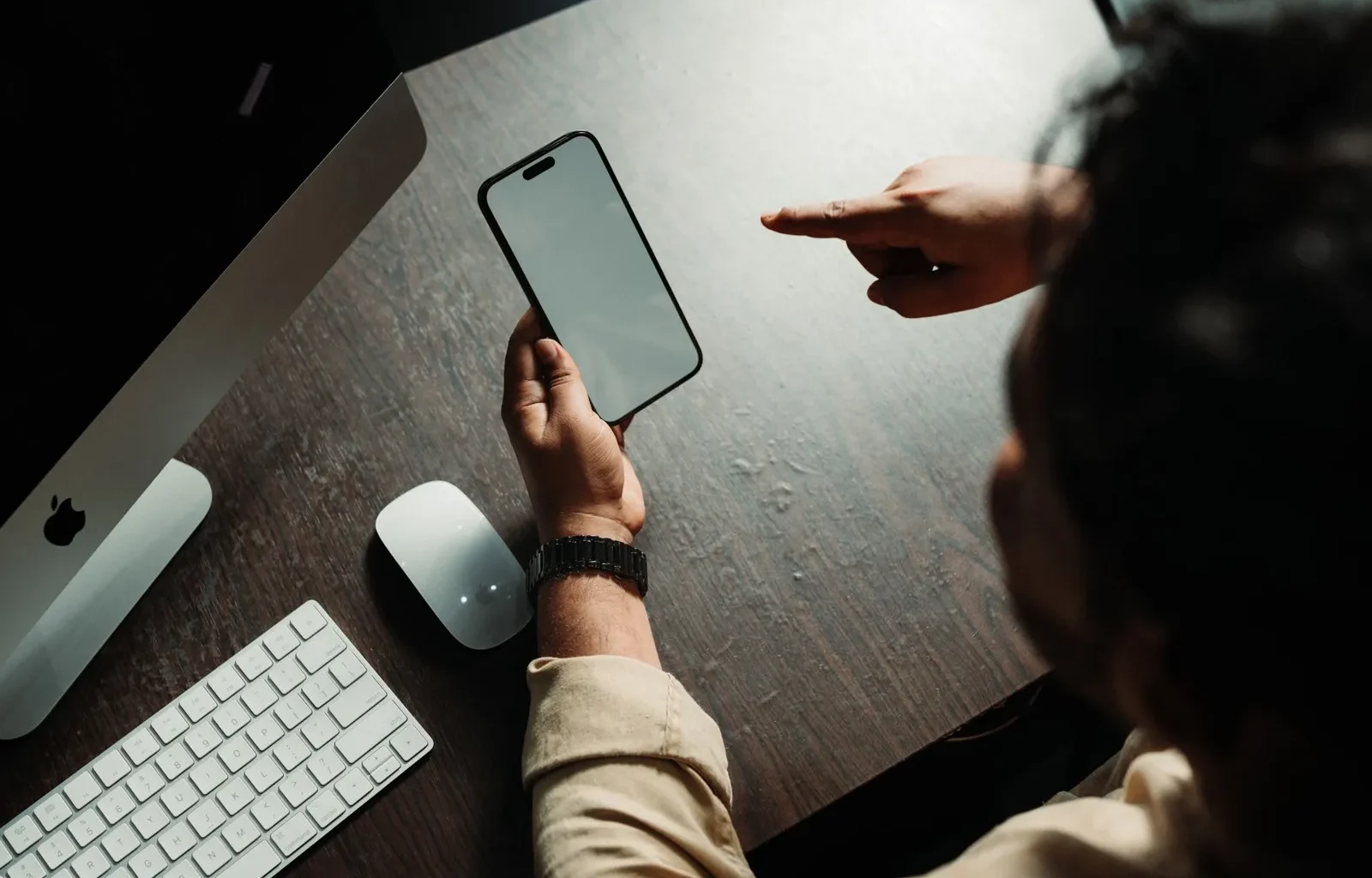 Person holding an iPhone at a desk, the work setting where Siri AI French support will matter.