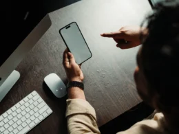 Person holding an iPhone at a desk, the work setting where Siri AI French support will matter.