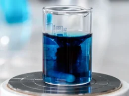 Close-up of a laboratory beaker of blue liquid, standing in for AI in health research studies