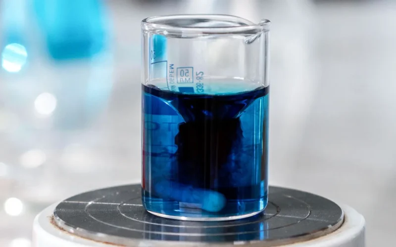 Close-up of a laboratory beaker of blue liquid, standing in for AI in health research studies