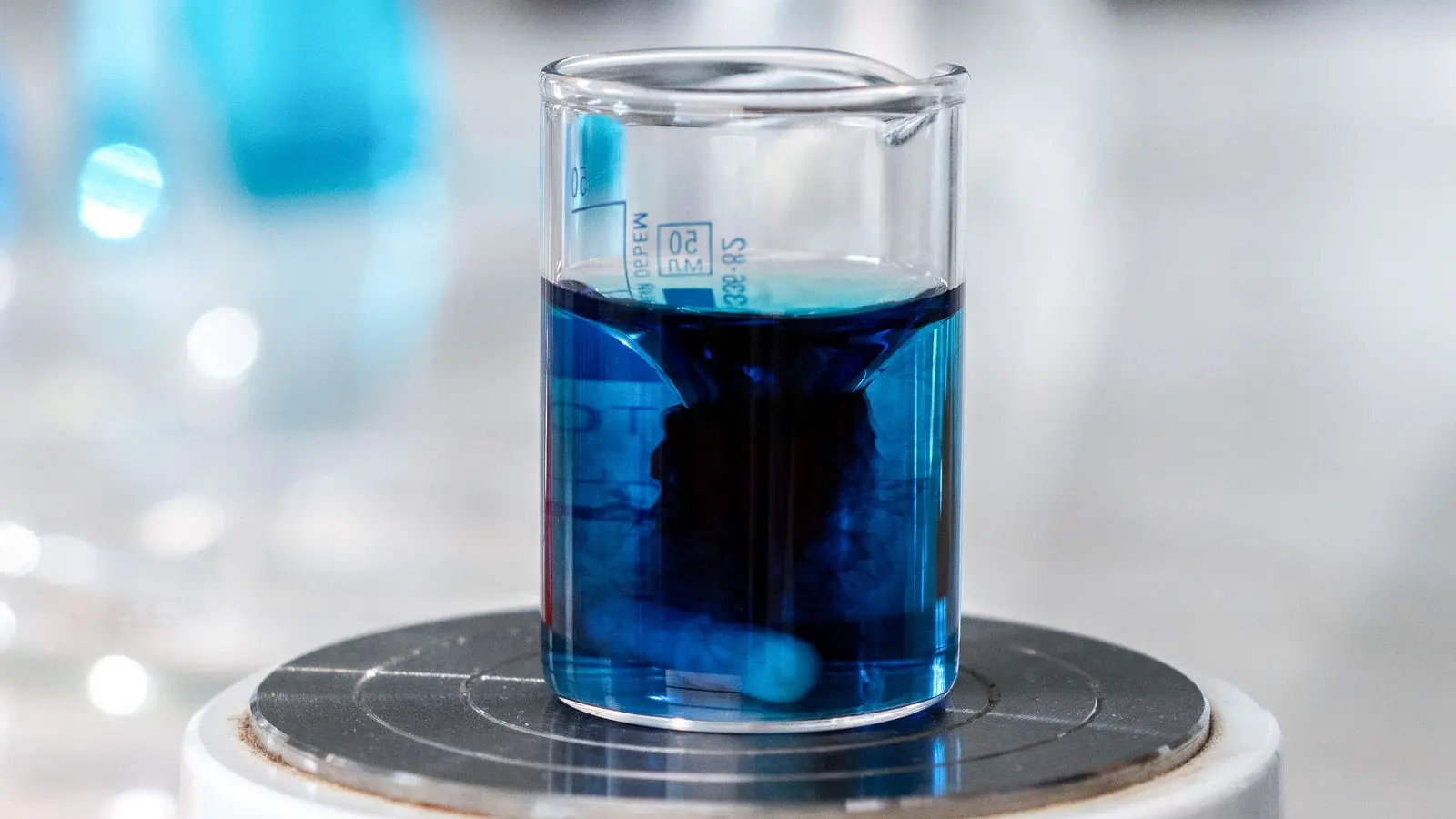 Close-up of a laboratory beaker of blue liquid, standing in for AI in health research studies