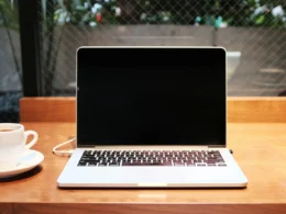 A laptop computer beside a coffee mug on a table