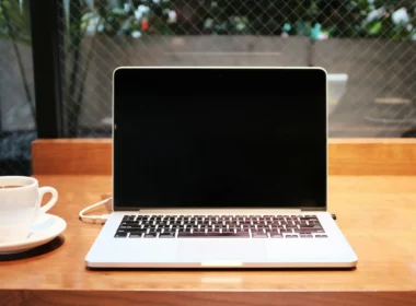 A laptop computer beside a coffee mug on a table