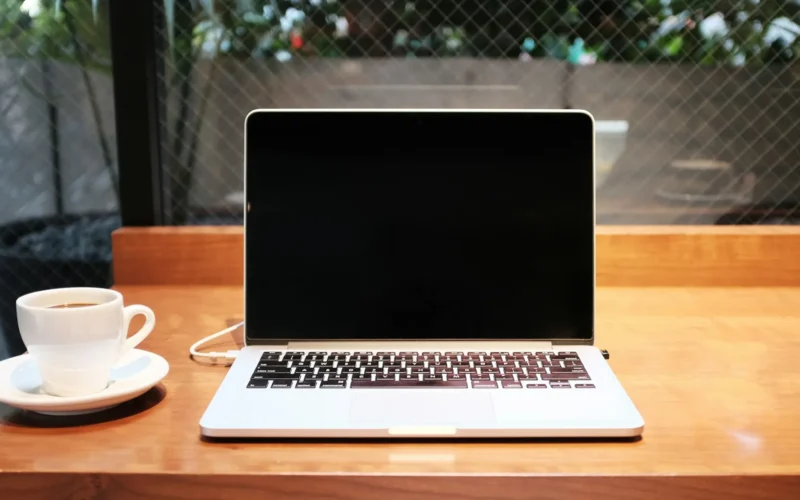 A laptop computer beside a coffee mug on a table