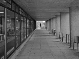 Long concrete walkway with windows and a distant person