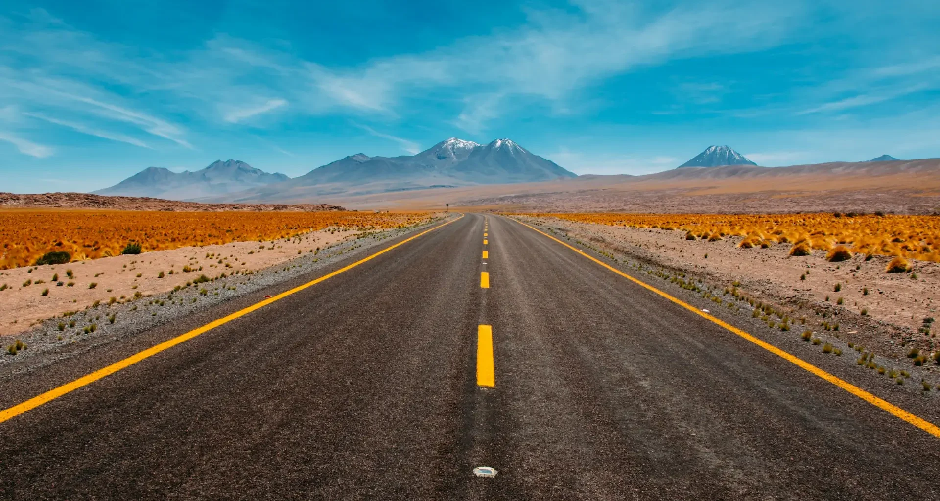 A single straight road running toward distant mountains in a desert