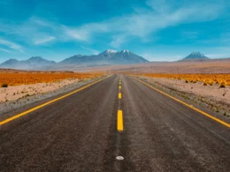 A single straight road running toward distant mountains in a desert