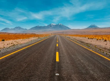 A single straight road running toward distant mountains in a desert