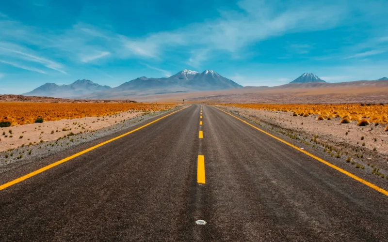 A single straight road running toward distant mountains in a desert