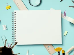 A magnifying glass lying beside sheets of white printer paper on a desk