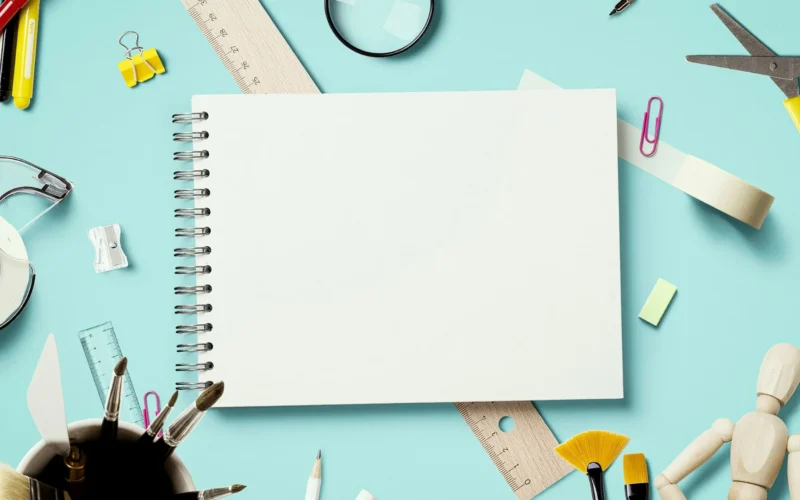 A magnifying glass lying beside sheets of white printer paper on a desk