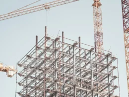 Gray metal building frame beside a tower crane during the day