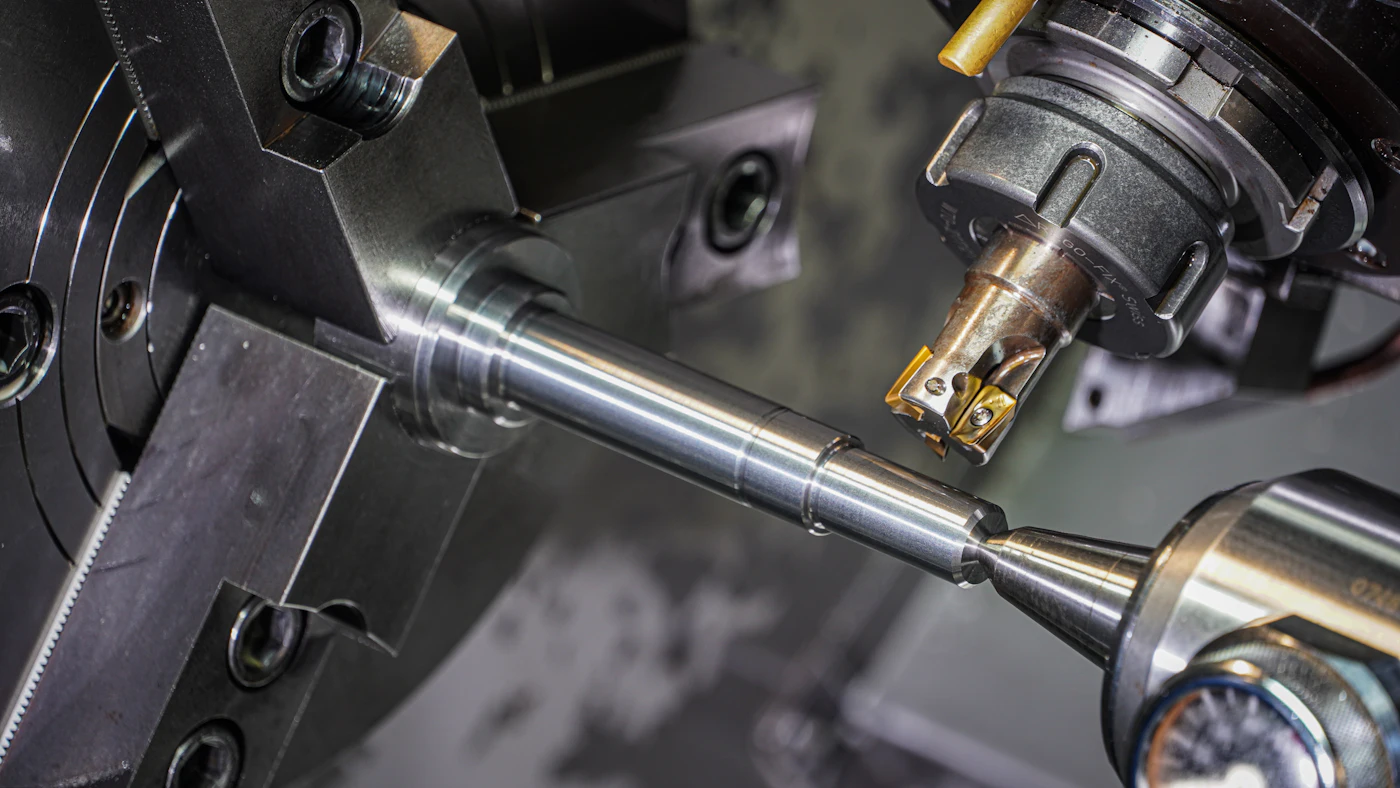 Steel rod clamped in a lathe chuck as a cutting tool machines its surface in a workshop
