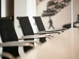 Black office chairs with chrome arms in a row at a conference table