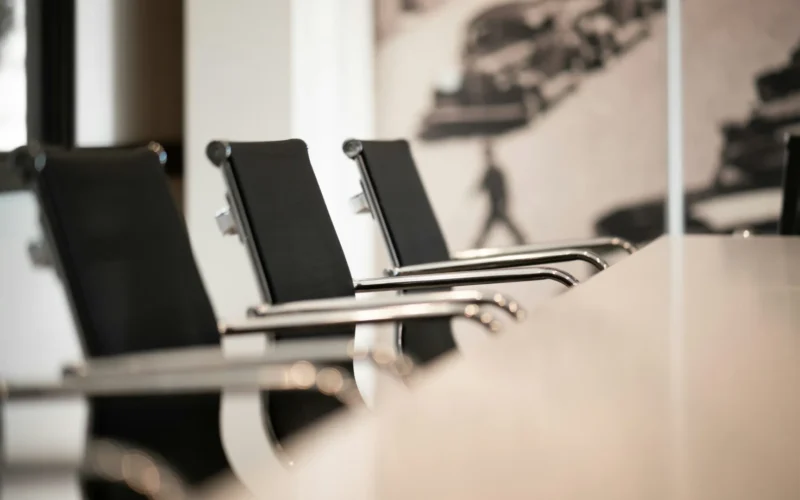 Black office chairs with chrome arms in a row at a conference table