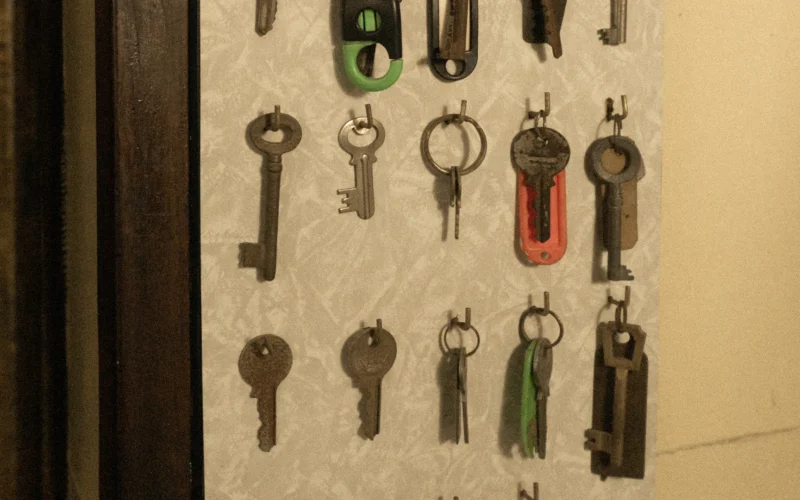 Rows of old metal keys hanging from hooks on a pale patterned wall