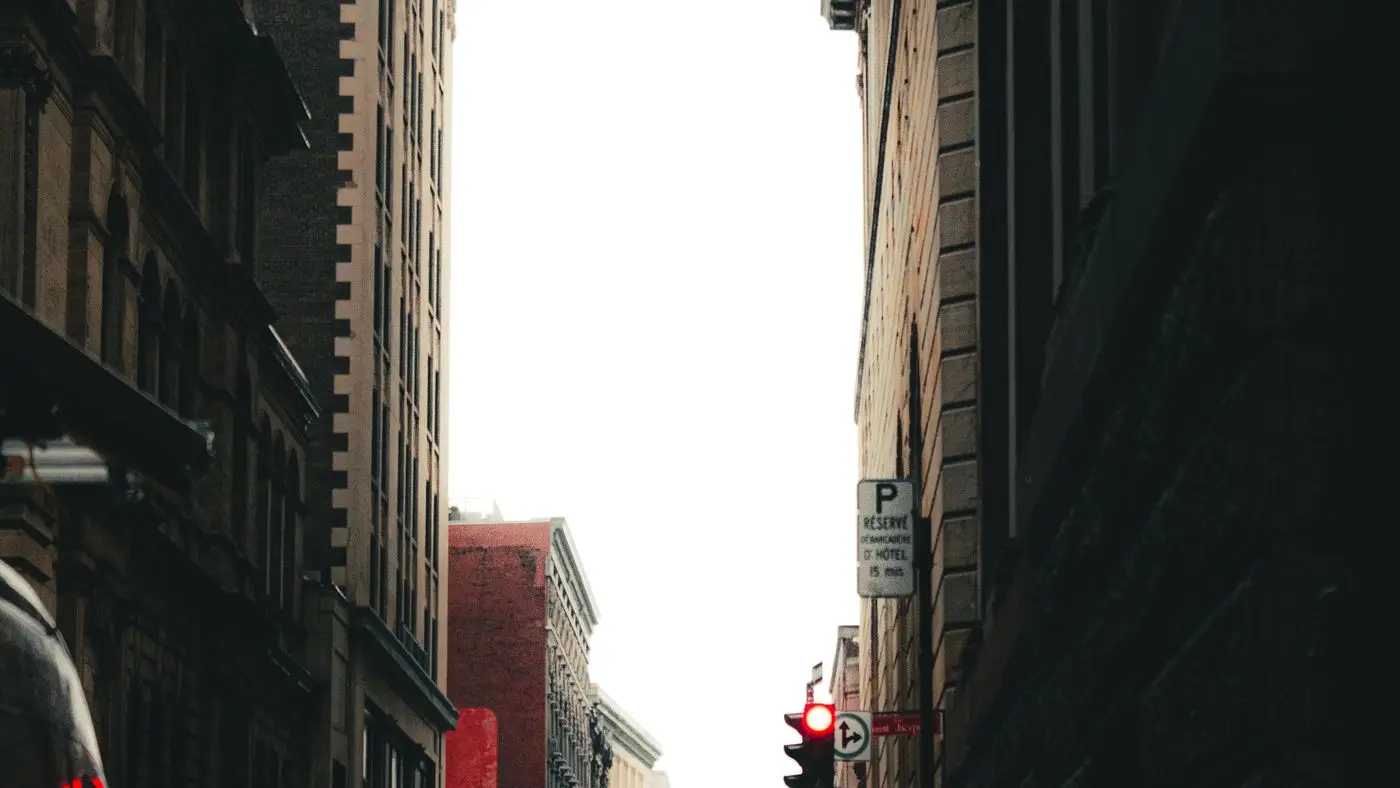Narrow street in Old Montreal between stone buildings, with a traffic light showing red