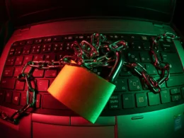 Padlock and chain lying across a laptop keyboard under red and green light, a symbol of AI API key security