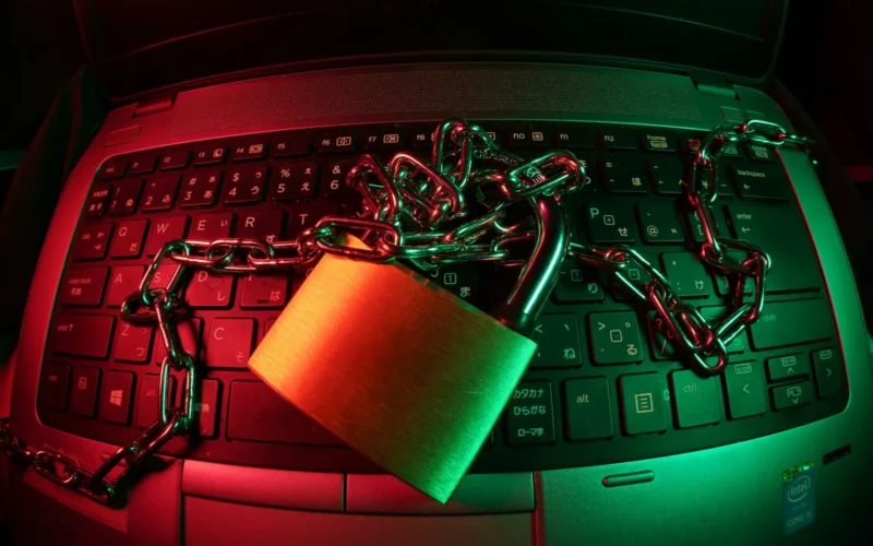 Padlock and chain lying across a laptop keyboard under red and green light, a symbol of AI API key security