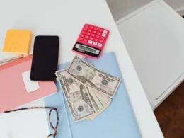 Calculator, banknotes, notebook and phone on a white desk, ready to check Fable 5.1 pricing against a budget
