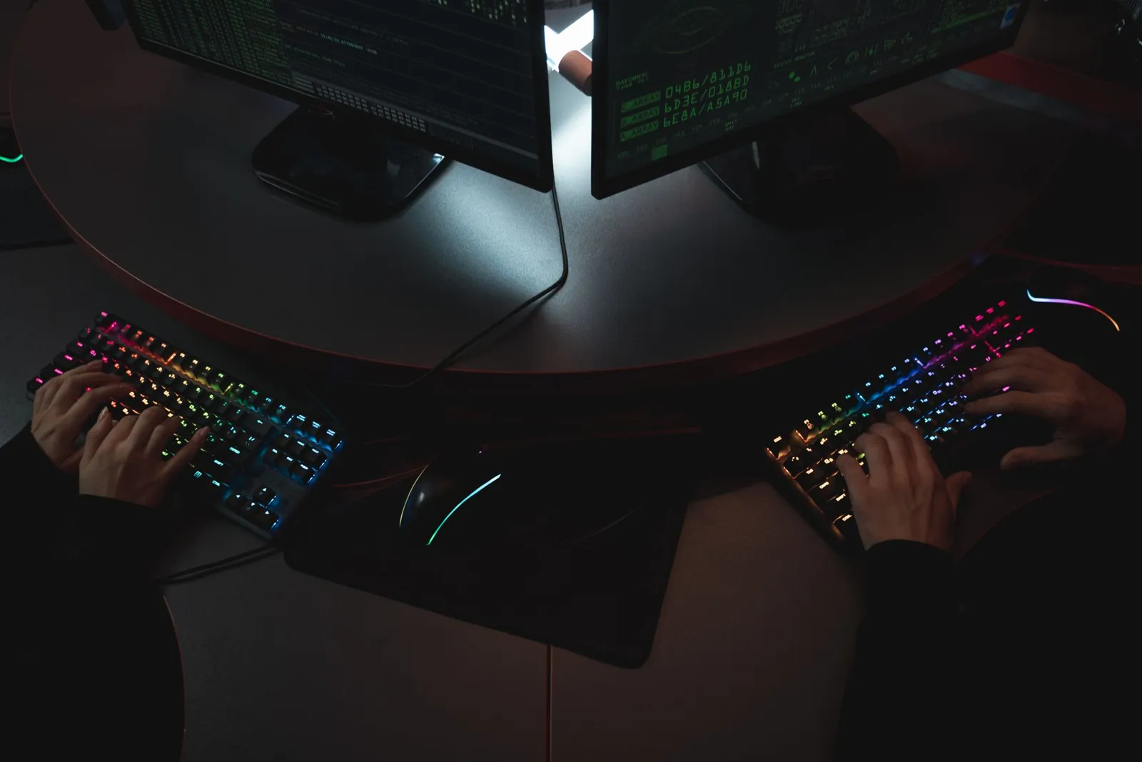 AI API key security: two people typing on lit keyboards in front of screens of code.