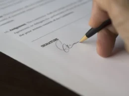 Hand signing a contract, as a business accepts the Muse Model License terms for Muse Spark Open