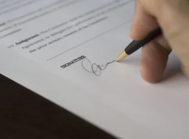 Hand signing a contract, as a business accepts the Muse Model License terms for Muse Spark Open