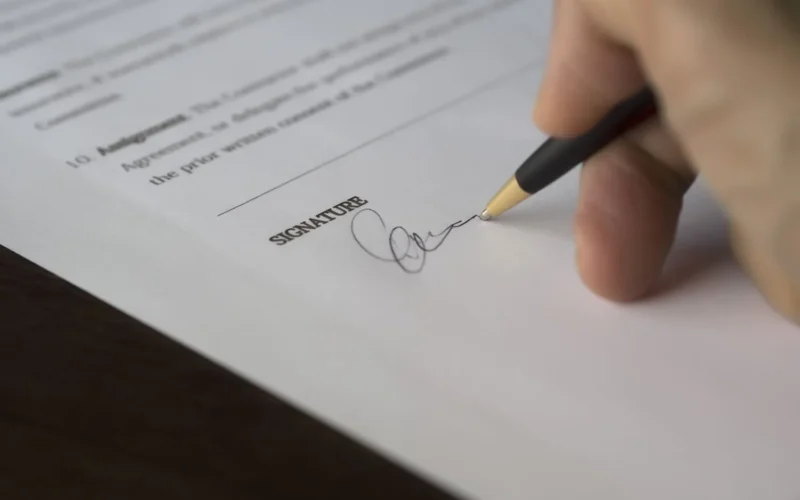Hand signing a contract, as a business accepts the Muse Model License terms for Muse Spark Open