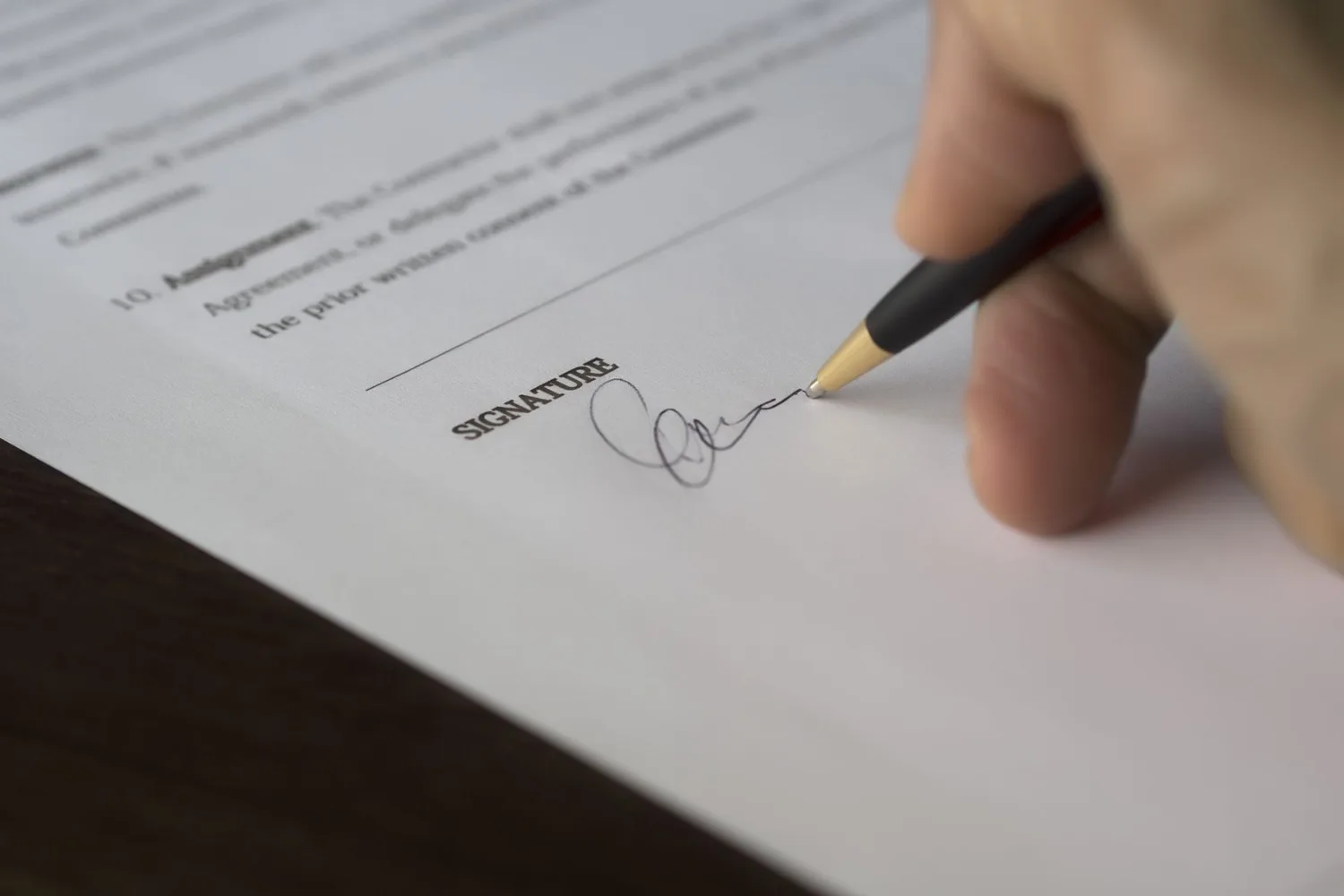Hand signing a contract, as a business accepts the Muse Model License terms for Muse Spark Open