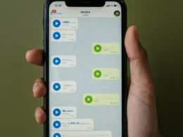 Hand holding a smartphone showing a messaging app.