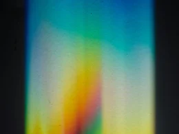 A beam of light splitting into a rainbow spectrum through a prism on a black surface