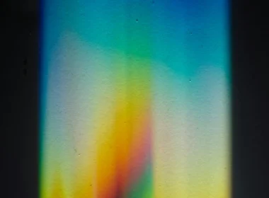 A beam of light splitting into a rainbow spectrum through a prism on a black surface