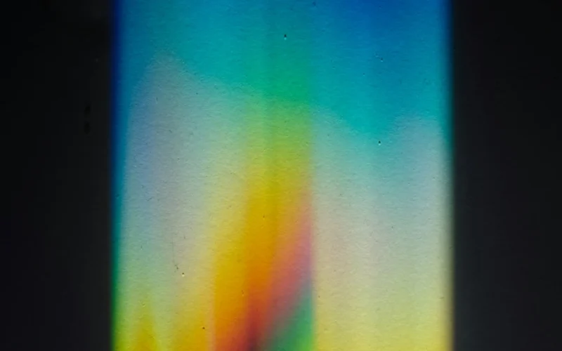 A beam of light splitting into a rainbow spectrum through a prism on a black surface
