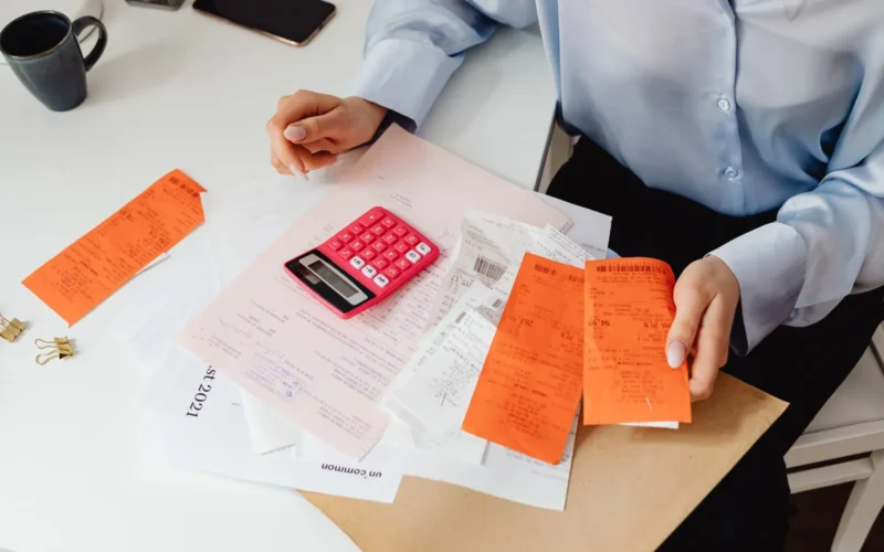 A person checking receipts and invoices with a calculator, the accounts payable desk where payment fraud controls start