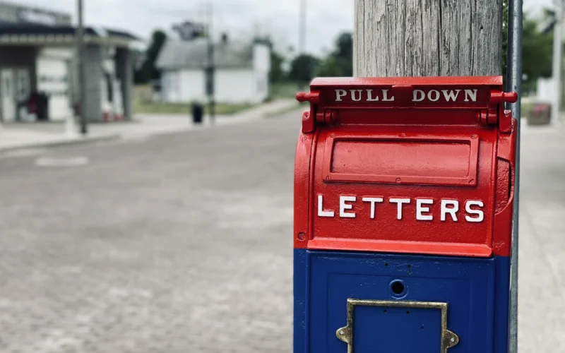 Red mail box on brown wooden post